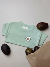 Load image into Gallery viewer, flat lay of avocado-themed baby t-shirt with whole and halved avocados