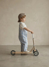 Load image into Gallery viewer, Child wearing blue gingham dungaree set with embroidered pigeon t-shirt riding a scooter