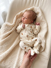 Load image into Gallery viewer, Baby wearing a Highland cow footed zip-up onesie on a soft muslin blanket