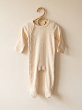 Load image into Gallery viewer, Organic ribbed footed baby sleepsuit in cream made from 95% organic cotton hanging on a wooden hanger.