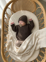 Load image into Gallery viewer, Sleeping baby wearing an oversized chunky knit jumper in khaki made from 100% cotton, styled with neutral ribbed leggings inside a natural rattan bassinet.