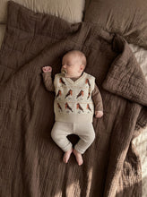 Load image into Gallery viewer, Baby wearing a cream robin knit vest layered over a long sleeve top with neutral knit trousers.