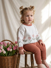 Load image into Gallery viewer, Toddler wearing the oversized organic cotton Tulip Knit Jumper beside a basket of fresh tulips in a natural Scandinavian-inspired lifestyle setting.