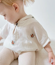 Load image into Gallery viewer, side view of baby in cream muslin poncho with floral pattern – soft cotton fabric