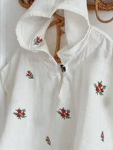 Load image into Gallery viewer, front view of muslin baby poncho displayed on hanger – floral embroidery details