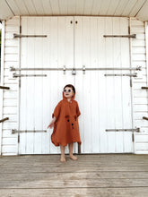Load image into Gallery viewer, child wearing burnt orange muslin poncho in front of white doors – lightweight summer outfit