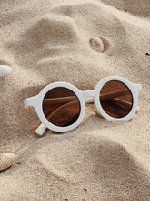 Load image into Gallery viewer, coconut colour baby sunglasses placed on sand with seashells – summer-themed flat lay