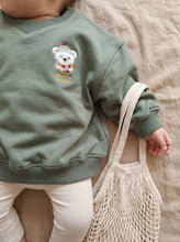 Load image into Gallery viewer, Baby wearing sage organic cotton sweatshirt with embroidered winter bear and Bear-y Warm slogan
