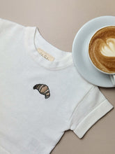 Load image into Gallery viewer, close-up of croissant embroidery on cream knit fabric – baby and kids tee
