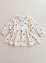 Load image into Gallery viewer, Cream organic cotton baby and toddler dress with all-over croissant print, rounded collar and long sleeves.
