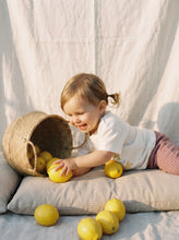 Load image into Gallery viewer, Toddler playing with lemons beside wicker basket while wearing organic cotton Isn’t She Lovely graphic t-shirt
