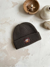 Load image into Gallery viewer, Khaki cotton knit beanie hat with Highland cow patch for babies and children on a neutral textured background.
