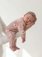 Load image into Gallery viewer, Newborn baby sleeping while wearing a soft pink organic cotton knitted romper with white daisy flowers. Cozy long sleeve baby knitwear for autumn and winter.
