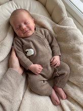 Load image into Gallery viewer, Sleeping newborn wearing an organic cotton sheep knit baby onesie while resting on a soft cream knitted blanket.
